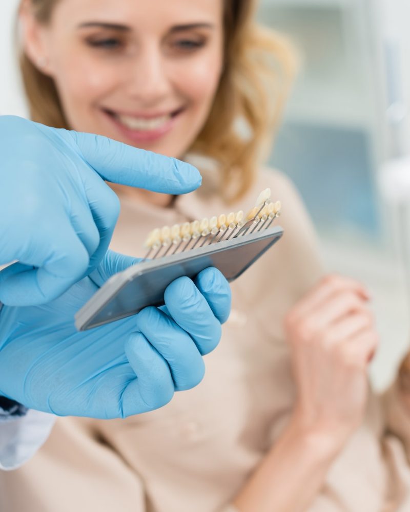 Doctor choosing tooth implants with female patient in modern dental clinic